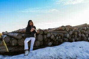 middle aged woman wearing winter clothes using smart phone in the snow over a mountain photo