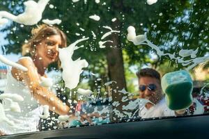 happy middle aged couple with man sitting on wheelchair washing car at public car wash photo