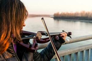 atractivo medio Envejecido mujer jugando un eléctrico violín al aire libre foto