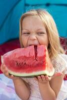 portrait of pretty little girl is having fun while eating a slice of watermelon photo