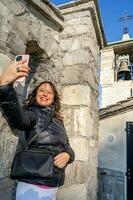 middle aged woman wearing winter clothes taking a selfie over a mountain photo