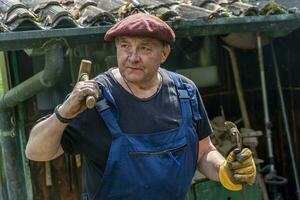 portrait of mature blacksmith. Iron worker in workshop outdoors in the countryside photo