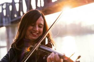 attractive middle aged woman playing an electric violin outdoors photo