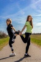 couple of pretty athletic women doing gymnastics exercises outdoors photo