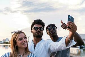 pequeño grupo de multiétnico amigos teniendo divertido tomando un selfie con teléfono inteligente foto