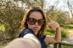 beautiful woman taking selfie outdoors during a happy walk in the countryside photo