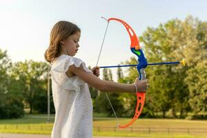 cute little girl is playing with a toy bow and arrow photo
