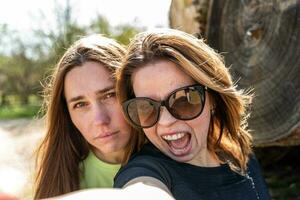 couple of pretty friendly women taking a selfie making funny faces photo