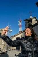 middle aged woman wearing winter clothes taking a selfie over a mountain photo