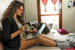 young woman is working on the computer on sofa at home photo