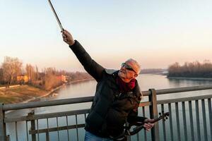 atractivo medio Envejecido músico hombre jugando un eléctrico violín al aire libre foto