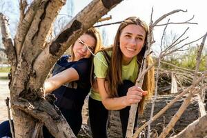 couple of female athletes having fun while climbing on cut logs outdoors photo