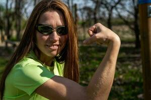 portrait of young woman showing muscles during outdoor workout photo