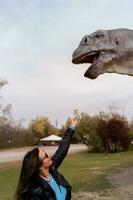 middle aged tourist having fun feeding a flower to a life-size model dinosaur photo