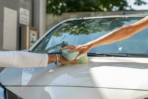 hands of two lovers touch on the hood while washing the car photo