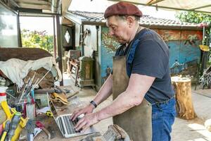 portrait of mature blacksmith. Worker on the computer in the laboratory in the countryside photo