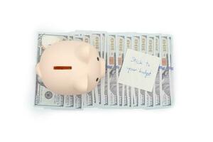Text written note STICK TO YOUR BUDGET and Piggy bank on US Dollars. concept of financial planning to save money by spending less. Finance and business concept. isolated background. photo