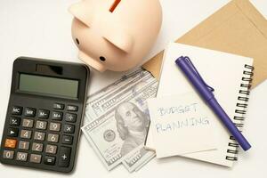 dinero presupuesto planificación. cerdito banco con calculadora y cuadernos en blanco fondo, financiero objetivo concepto. foto