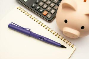 Piggy bank with calculator and notebooks on white background and copy space, financial goal concept. photo