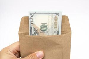 Hands holding open craft paper envelope with hundred dollars on isolated background with copy space. photo