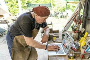 portrait of mature blacksmith. Worker on the computer in the laboratory in the countryside photo