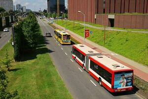 KATOWICE, POLAND, 2021 - Two public buses, yellow one Mercedes O530 Citaro G line number 673, red one MAN NG 313 line number 808, follows their routes in the area Katowice Cultural Zone. photo