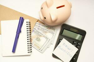 dinero presupuesto planificación. cerdito banco con calculadora y cuadernos en blanco fondo, financiero objetivo concepto. foto