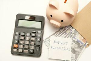 Money budget planning. Piggy bank with calculator and notebooks on white background, financial goal concept. photo