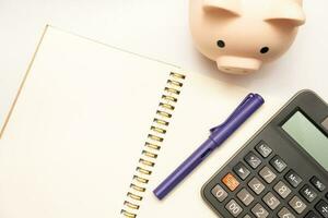 cerdito banco con calculadora y cuadernos en blanco antecedentes y Copiar espacio, financiero objetivo concepto. foto