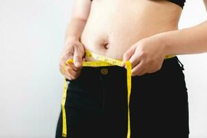 Overweight woman measuring her fat belly with a measuring tape, overweight fatty belly of woman, fat woman, fat girl, Woman diet lifestyle concept to reduce belly. photo