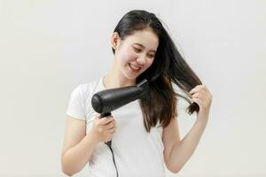 contento asiático joven mujer el secado pelo en blanco fondo, tratamiento pelo concepto, dañado cabello, belleza salón. foto