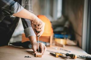 asiático carpintero trabajando con equipo herramientas en de madera mesa en carpintería tienda. concepto trabajando de carpintero. profesional trabajando de madera hombre. foto