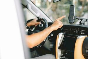 un hombre unidades un coche utilizando un GPS navegación sistema en su móvil teléfono mientras conduciendo, a encontrar su destino. transporte con tecnología concepto. foto