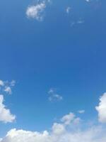 White clouds in the blue sky. Beautiful bright blue background. Light cloudy, good weather. Curly clouds on a sunny day. photo