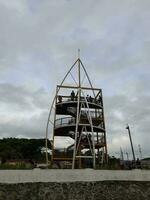 March 5, 2023 - Yellow tower ladder in the shore, Loang Baloq Beach, Mataram, Lombok island, Indonesia. Visitors, max. 10 people, can go upstair to enjoy and see the beach's view from atop photo