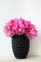 The peony or paeony pink flowers in vase at the shelf. Paeonia Sarah Bernhardt bouquet on grey background. Home interior concept photo