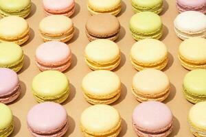An assortment of macarons are neatly arranged in rows on a flat surface photo