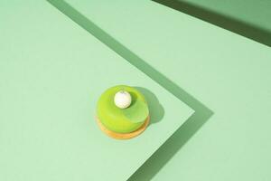 A freshly baked pastry with green and white icing, sitting atop a green-hued surface photo