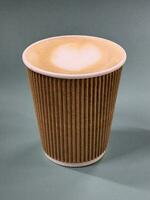 Cappuccino in a paper cup. Coffee in a paper cup on a gray background photo