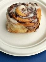 Sweet cake. Cinnabon on a white plate with a blue background. Cooking photo