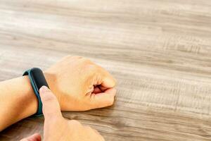 Female hand using smart watch on wooden table. photo