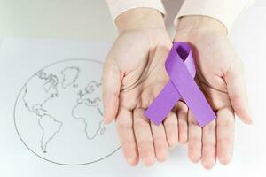 World Cancer Day, hand with ribbon symbol on world map background. photo