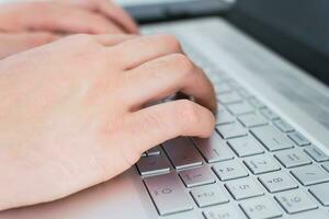 Close up of male hands typing on laptop keyboard. photo