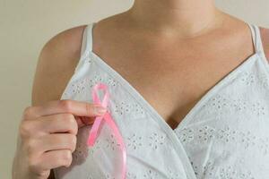 October Breast Cancer Awareness month, Woman in white dress with hand holding Pink Ribbon photo