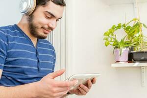 Young man in balcony with wireless headphones and digital tablet. photo