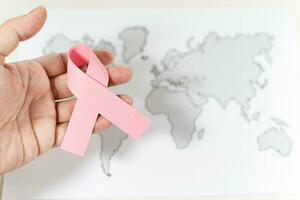 World Cancer Day, hand with ribbon symbol on world map background. photo