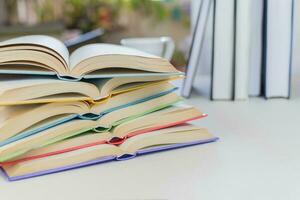 Close up, Desk with stack of open study books. Textbooks for the student, university. Study from home. Distance education concept. photo