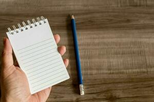 Female hand with notebook on wooden desk. Business, education and people concept. photo