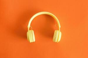 Top view of yellow headphones. Entertainment concept. On pastel orange background. photo