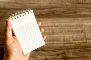 Female hand with notebook on wooden desk. Business, education and people concept. photo